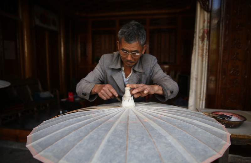 Un artisan travaille sur un parapluie en papier huilé dans le village de Xingyang