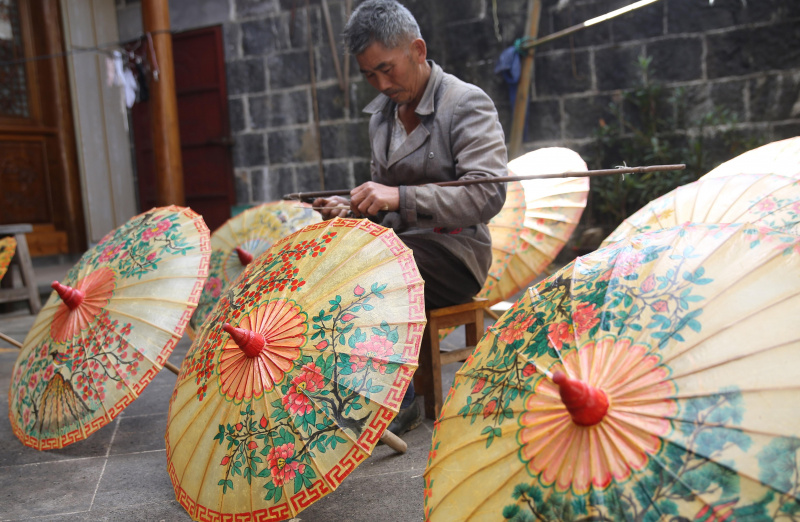 Un artisan travaille sur un parapluie en papier huilé dans le village de Xingyang