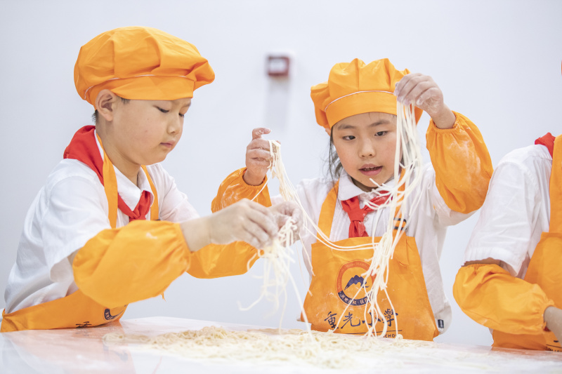 Des élèves apprennent à faire des nouilles en classe à l'école primaire de Chongguang à Chongqing
