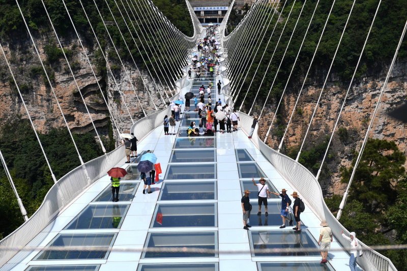 Des touristes marchent sur un pont de verre dans le Grand Canyon de Zhangjiajie