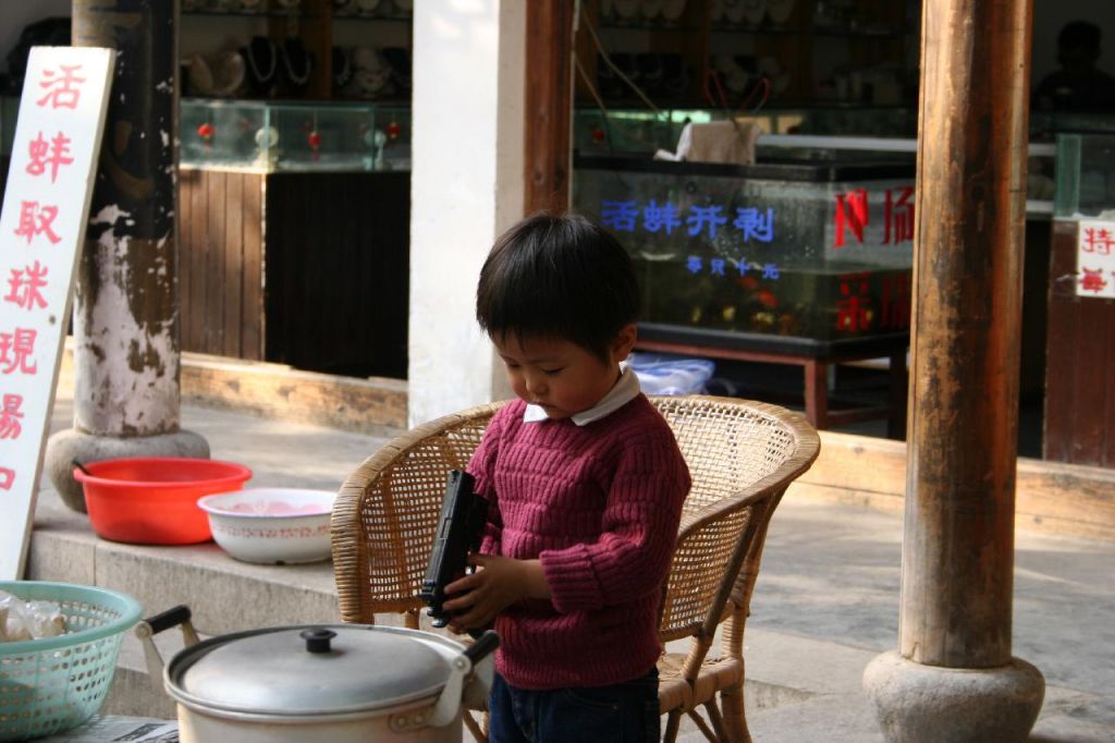 Enfant chinois qui joue avec une arme à feu