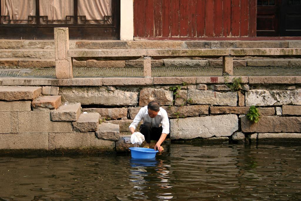Chinois lavant ses vêtements dans la rivière