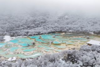 Un ensemble d'étangs colorés dans le site touristique de Huanglong recouvert de neige