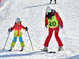 Une monitrice apprend à un enfant à faire du ski dans une station de sports d'hiver à Shijiazhuang