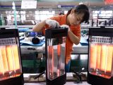 Une ouvrière contrôle des radiateurs électriques dans une entreprise de Foshan