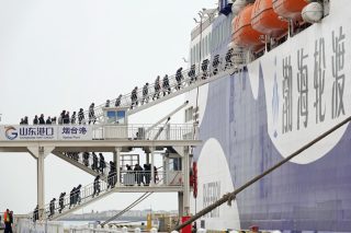 Des passagers montent à bord d'un bateau au port de Yantai
