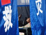 Un habitant sinistré regarde son téléphone portable dans un site de relogement temporaire à Guzan