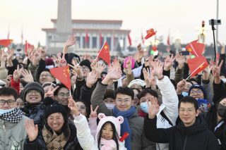 Des personnes saluent après une grande cérémonie de lever du drapeau national sur la place Tian'anmen
