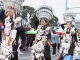 Des habitants locaux vêtus de costumes traditionnels de l'ethnie Yi marchent dans une rue