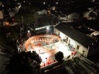 Photo aérienne de drone montrant des acteurs exécutant une danse du dragon devant la salle ancestrale de la famille Zhou dans le village de Fengjiangzhou de la ville de Zhuji
