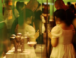 Des touristes visitent une exposition présentant des reliques restaurées au Musée du Palais de Shenyang