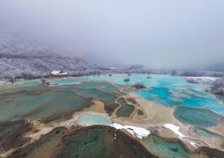 Un ensemble d'étangs colorés dans le site touristique de Huanglong recouvert de neige