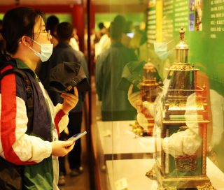 Des touristes visitent une exposition présentant des reliques restaurées au Musée du Palais de Shenyang