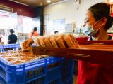 Un membre du personnel met en ordre des gâteaux de lune dans un magasin de gâteaux de lune à la mode de Hainan