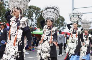 Des habitants locaux vêtus de costumes traditionnels de l'ethnie Yi marchent dans une rue