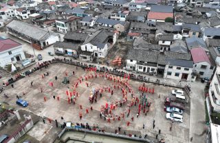 Photo aérienne de drone montrant des acteurs exécutant une danse du dragon devant la salle ancestrale de la famille Zhou dans le village de Fengjiangzhou de la ville de Zhuji