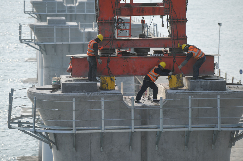 Des ouvriers travaillent sur un chantier de pose des poutrelles du pont de la baie de Meizhou du chemin de fer à grande vitesse Fuzhou-Xiamen