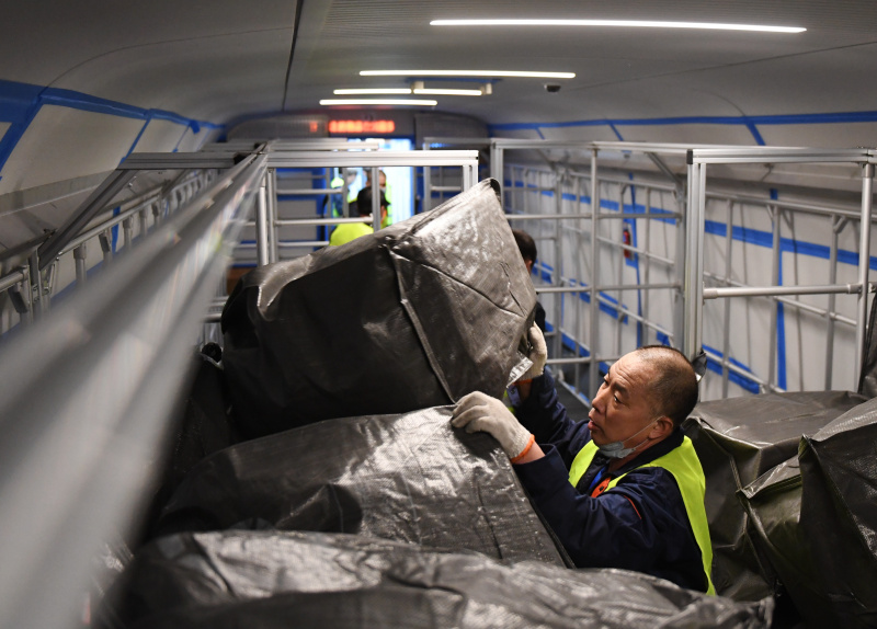 Un travailleur charge des colis sur un train à grande vitesse Fuxing à la Gare de l'ouest de Beijing à Beijing