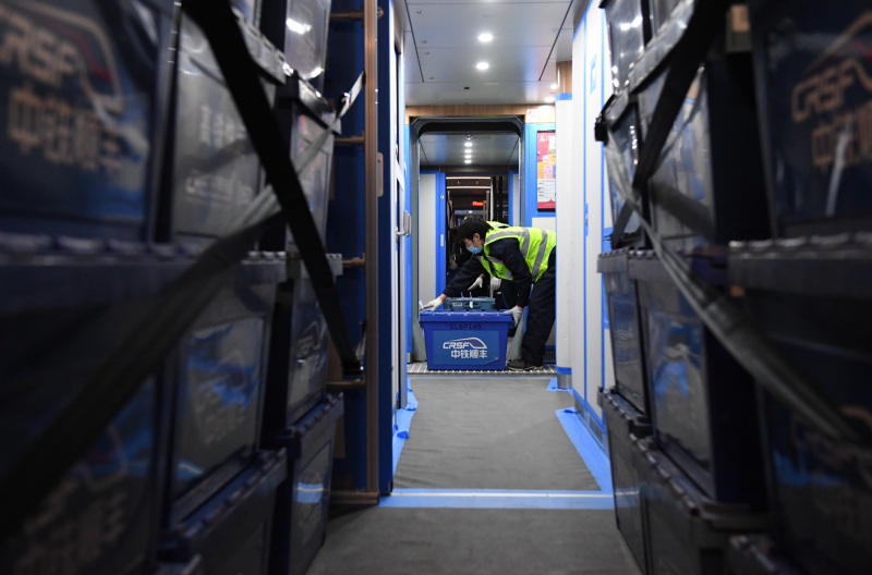 Des travailleurs chargent des colis sur un train à grande vitesse Fuxing à la Gare de l'ouest de Beijing à Beijing
