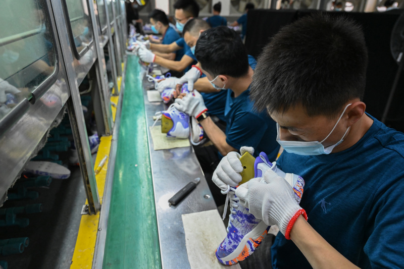 Des employés travaillent sur une ligne de production d'une entreprise de chaussures de sport