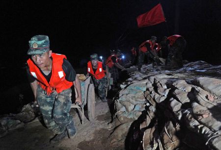(miniature) Des policiers arm&eacute;s transportent des sacs de sable sur une digue &agrave; Poyang