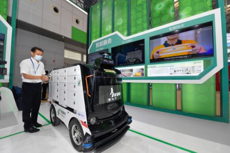 (miniature) Un membre du personnel présente un véhicule de livraison autonome lors du Congrès mondial de l'intelligence