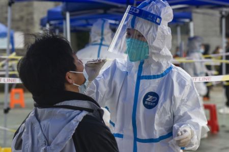 (miniature) Une professionnelle de santé prélève un échantillon de gorge sur un habitant pour des tests d'acide nucléique dans un site de dépistage de l'arrondissement de Zhenhai de la ville de Ningbo