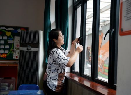 (miniature) Une enseignante vérifie que les fenêtres sont bien fermées dans une école primaire dans l'arrondissment de Huangpu