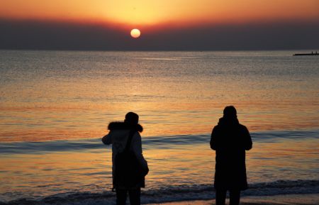 (miniature) Des gens admirent le lever du soleil sur la plage à Rizhao