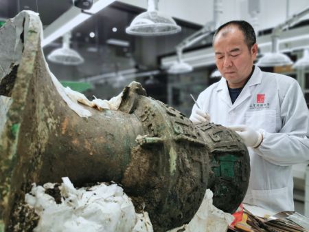 (miniature) Cette photo prise en mars 2022 montre Guo Hanzhong en train de nettoyer un récipient en bronze au musée de Sanxingdui de la ville de Guanghan