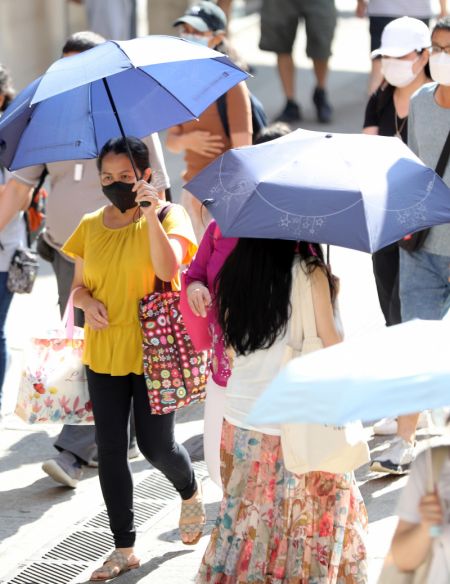 (miniature) Des gens utilisent des ombrelles pour se protéger du soleil tout en marchant dans la rue lors d'une journée chaude d'été à Hong Kong