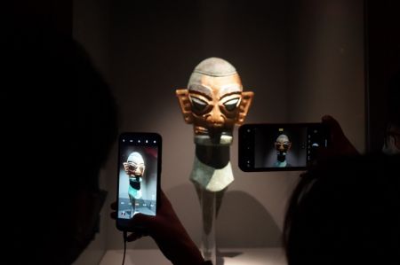 (miniature) Les visiteurs prennent une photo d'une exposition au musée de Sanxingdui à Guanghan