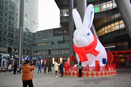 (miniature) Des gens posent pour des photos avec un lapin gonflable géant devant un centre commercial de Changsha