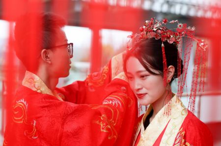 (miniature) Une mariée se fait ajuster sa parure de tête lors d'une cérémonie traditionnelle de mariage organisée à Guiyang