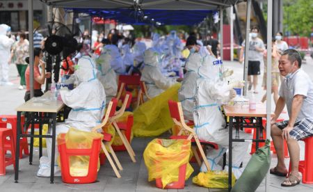(miniature) Des membres du personnel médical en combinaison de protection prélèvent des échantillons de gorge sur les habitants pour des tests d'acide nucléique dans le quartier de Baihedong dans l'arrondissement de Liwan à Guangzhou
