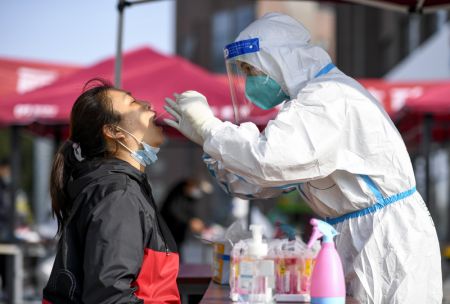 (miniature) Un travailleur médical prélève un échantillon de gorge sur une habitante pour le test d'acide nucléique dans un site d'échantillonnage à Yinchuan