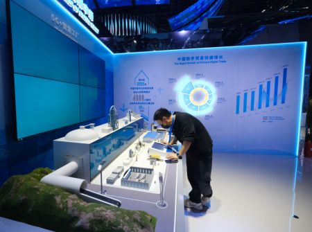 (miniature) Un membre du personnel vérifie une maquette d'usine intelligente 5G+ lors de la première Foire mondiale du commerce numérique