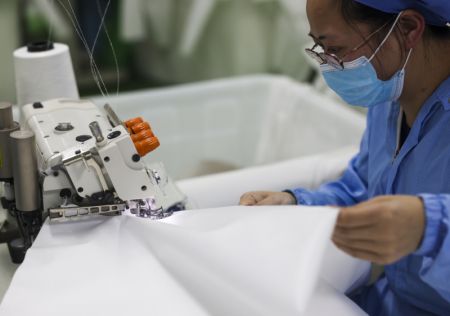 (miniature) Une employée fabrique des combinaisons de protection dans une usine du district de Fengdu de Chongqing