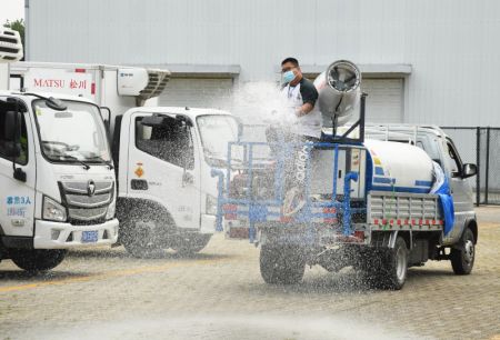 (miniature) Un membre du personnel d&eacute;sinfecte le parking d'une station d'entreposage pour transfert et de transport de l&eacute;gumes et fruits pour Beijing