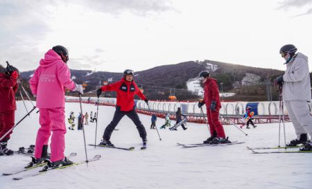 (miniature) Le moniteur Zhang Zhanhua (3e à droite) enseigne le ski dans la Station de ski du lac Songhua