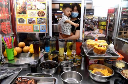 (miniature) Des personnes ach&egrave;tent des sp&eacute;cialit&eacute;s culinaires au march&eacute; de nuit de la tour du Tambour &agrave; Kaifeng