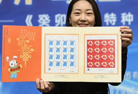 (miniature) Une femme présente un ensemble de timbres spéciaux marquant l'année du lapin lors de la cérémonie d'émission à Beijing