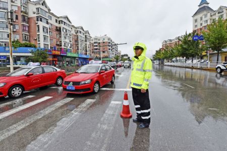 (miniature) Un policier chargé de la circulation en service sous des averses à Benxi