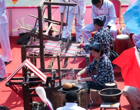 (miniature) Photo prise le 4 avril 2021 montre des femmes faisant la démonstration de la technique de récupération de soie dans les coeurs de vers à soie dans le culte de Canshen