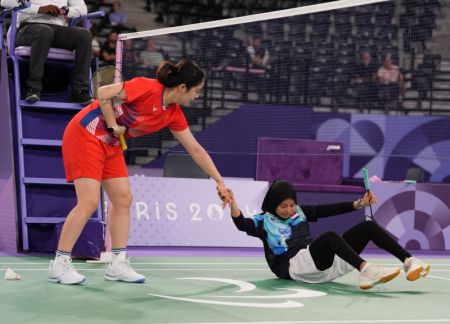 (miniature) Xiao Zuxian (à gauche) de la Chine aide Qonitah Ikhitiar Syakuroh de l'Indonésie pendant le match pour la médaille d'or du simple femmes SL3 de para badminton aux Jeux paralympiques de Paris 2024 à Paris