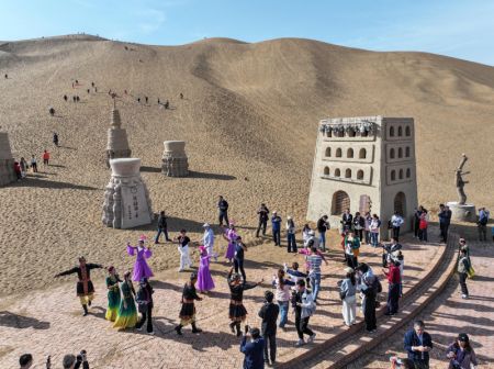 (miniature) Photo prise par un drone de participants au 6e Sommet mondial des médias en train de danser avec des artistes dans un désert à Turpan