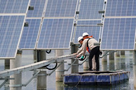 (miniature) Des ouvriers examinent les installations photovoltaïques dans une ferme aquatique dans l'arrondissement de Fengnan à Tangshan