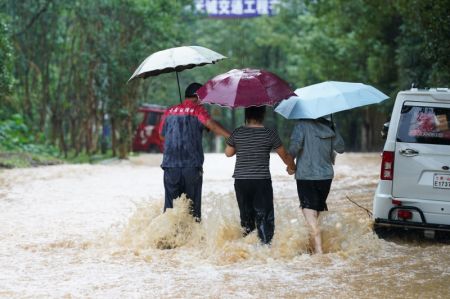 (miniature) Des personnes marchent sur une route inondée du district de Shexian