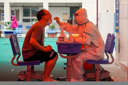 (miniature) Un professionnel de la santé prélève un échantillon par écouvillon sur un habitant dans un site de test d'acide nucléique de la COVID-19 de l'arrondissement de Guangling