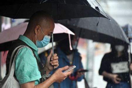 (miniature) Une personne attend son bus sous la pluie dans l'arrondissement de Haidian